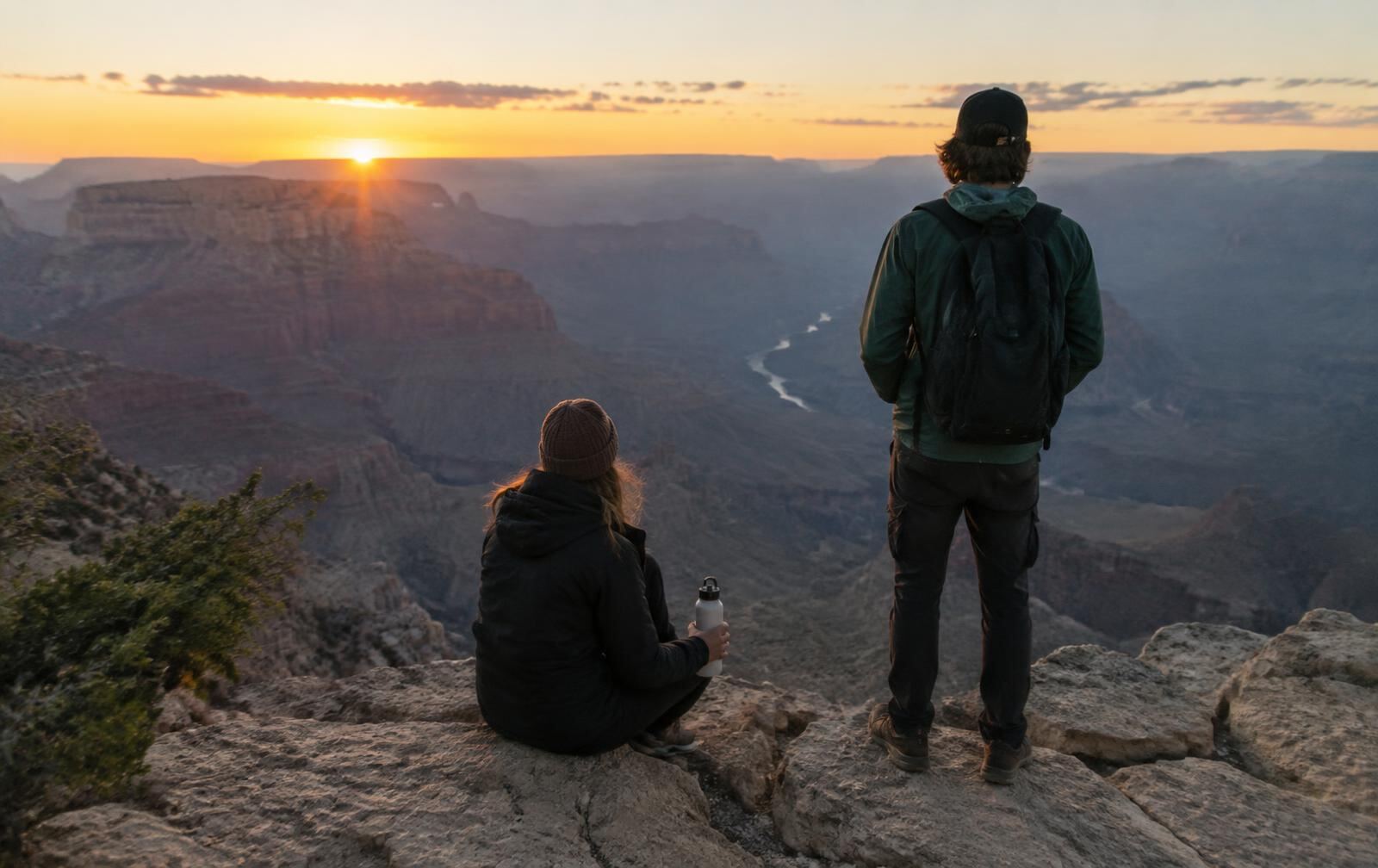 Two hikers at a canyon overlook at sunrise